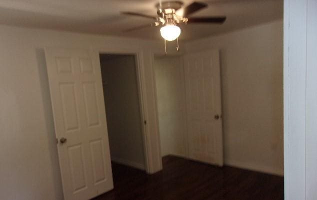 unfurnished bedroom with ceiling fan, a closet, and dark wood-type flooring