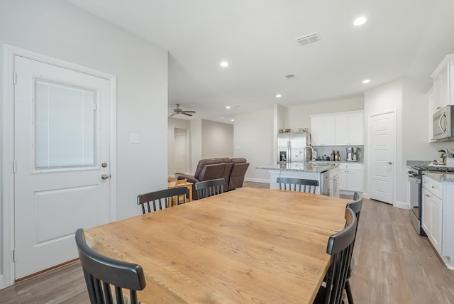 dining space featuring ceiling fan, light wood-type flooring, and sink