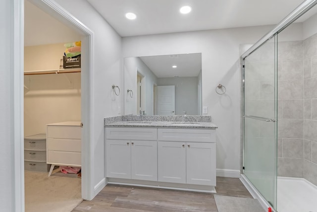 bathroom featuring a shower with shower door, vanity, and hardwood / wood-style flooring