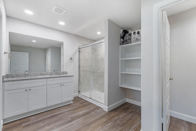 bathroom with a shower with shower door, hardwood / wood-style floors, and vanity