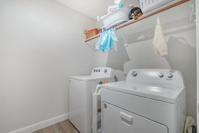 clothes washing area featuring washer and clothes dryer and light wood-type flooring