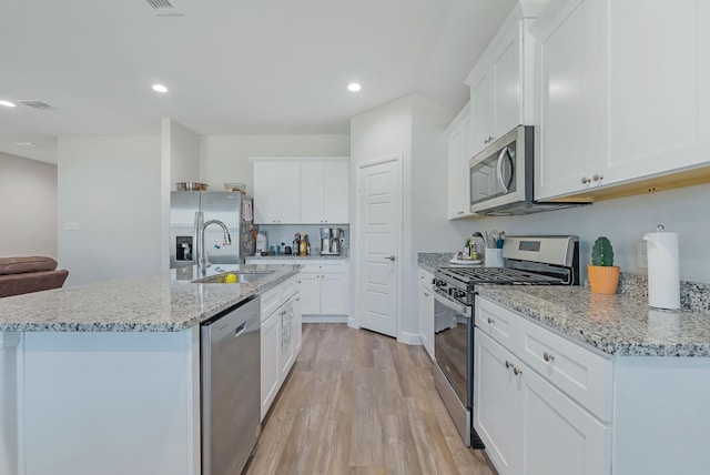 kitchen with sink, white cabinetry, light hardwood / wood-style flooring, appliances with stainless steel finishes, and light stone counters