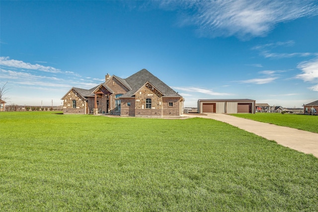 view of front of property featuring an outdoor structure, a garage, and a front lawn