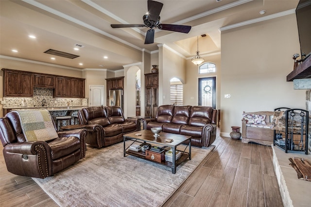 living room featuring ceiling fan, a stone fireplace, crown molding, and french doors