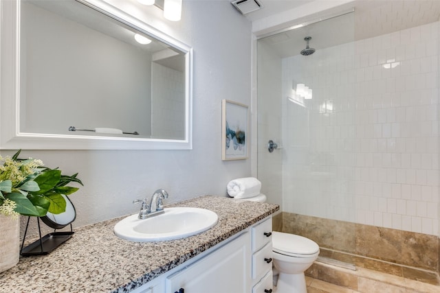 bathroom with toilet, vanity, and tiled shower