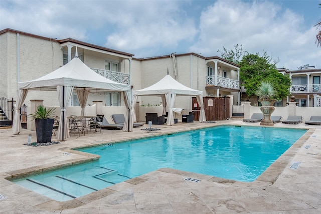 rear view of house featuring a patio, a balcony, and a community pool