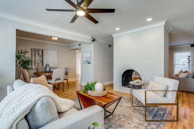 living room with a fireplace, wood-type flooring, ceiling fan, and ornamental molding