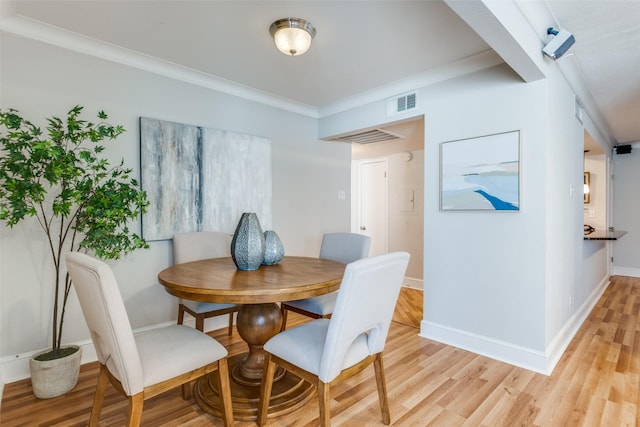 dining space with light hardwood / wood-style floors and ornamental molding