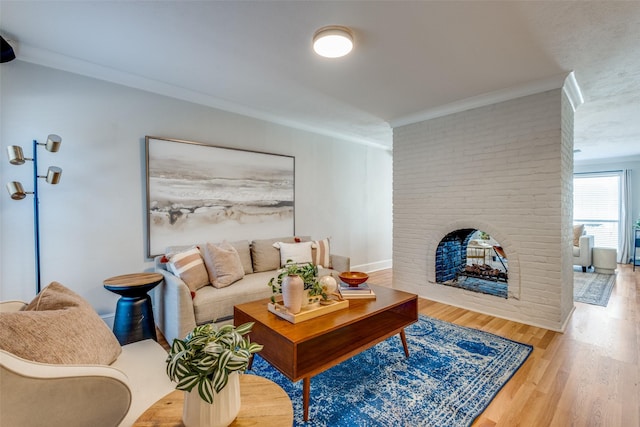 living room with wood-type flooring, ornamental molding, and a brick fireplace