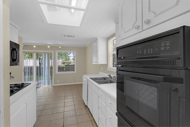 kitchen with light tile patterned flooring, black appliances, sink, a healthy amount of sunlight, and white cabinetry