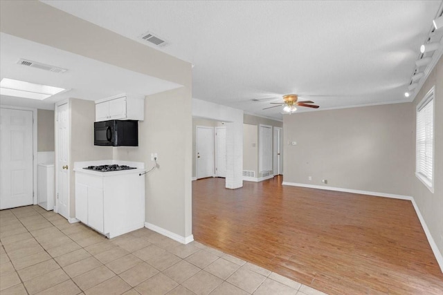 kitchen with ceiling fan, light tile patterned floors, gas cooktop, a textured ceiling, and white cabinets