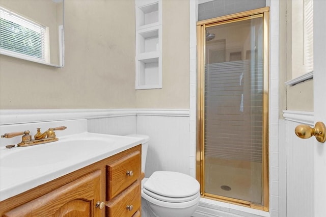 bathroom featuring toilet, vanity, built in features, and a shower with shower door