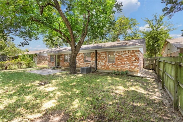 back of property with a lawn, a patio, and central AC