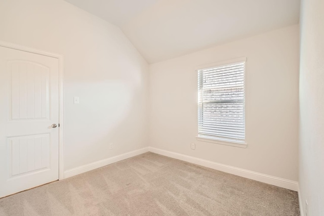 carpeted empty room featuring vaulted ceiling