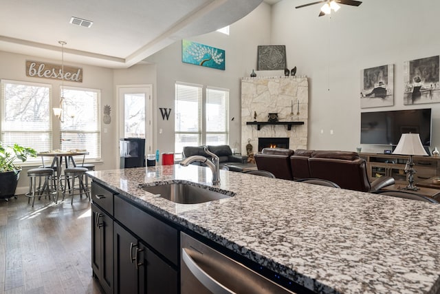 kitchen featuring sink, ceiling fan, light stone countertops, a fireplace, and decorative light fixtures