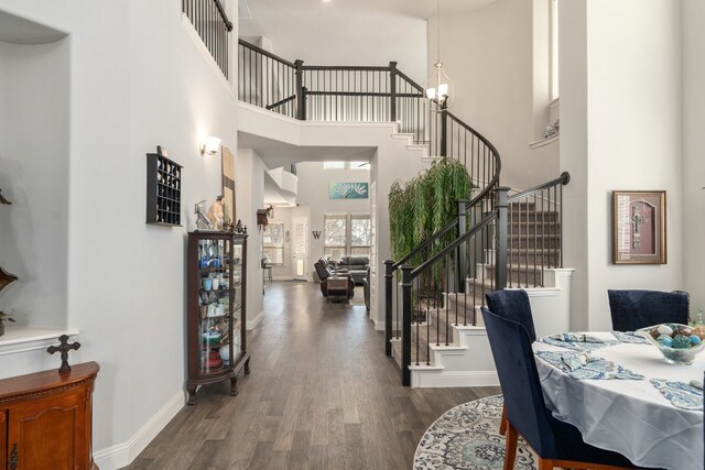 entrance foyer with a towering ceiling, dark hardwood / wood-style floors, and a notable chandelier