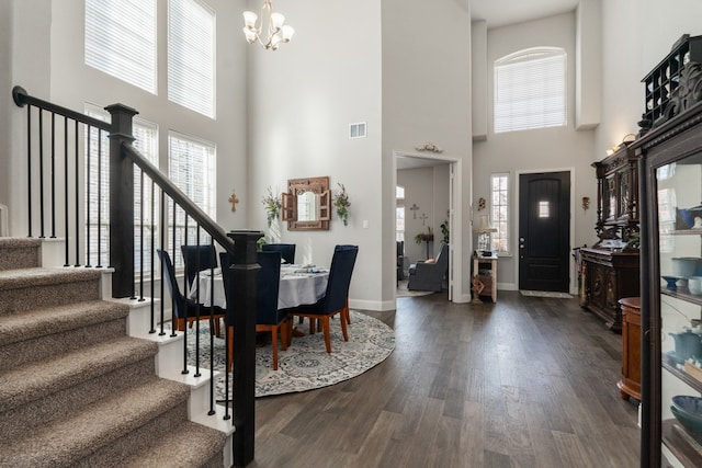 foyer entrance with visible vents, a notable chandelier, dark wood-style floors, stairway, and baseboards