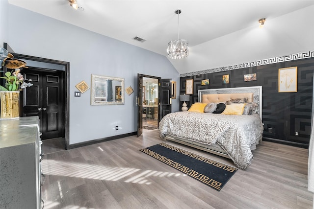 bedroom with hardwood / wood-style floors, vaulted ceiling, and a notable chandelier