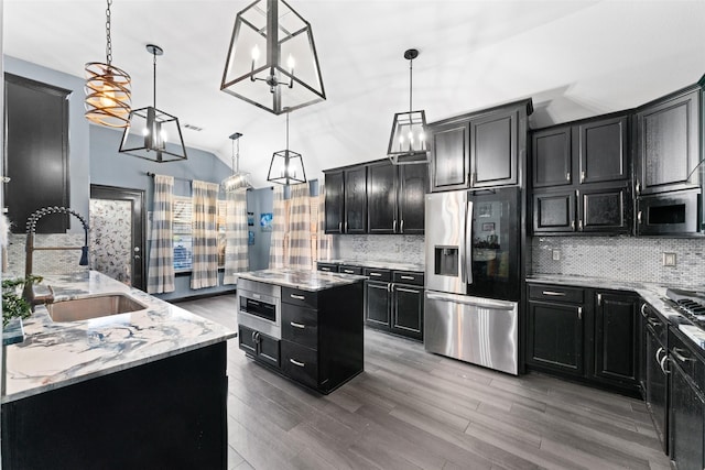 kitchen featuring sink, stainless steel refrigerator with ice dispenser, decorative light fixtures, a kitchen island, and light stone counters