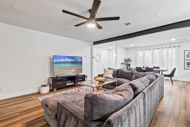 living room with ceiling fan, light hardwood / wood-style floors, and a textured ceiling