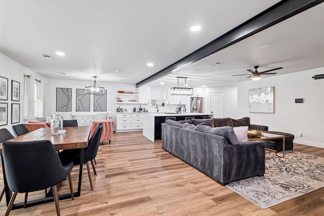 living room featuring beamed ceiling, light hardwood / wood-style flooring, and ceiling fan