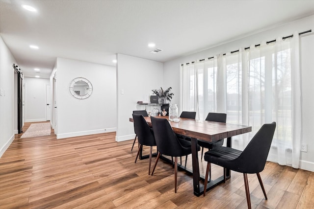 dining space featuring a barn door and light hardwood / wood-style floors