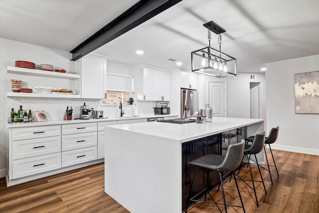 kitchen with a center island, white cabinets, hanging light fixtures, appliances with stainless steel finishes, and a breakfast bar area