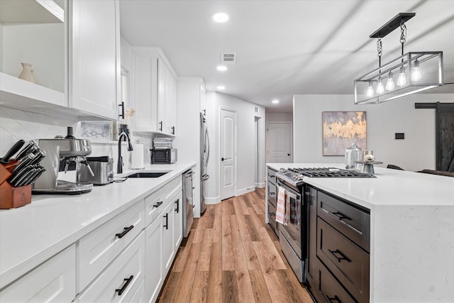 kitchen featuring white cabinets, sink, hanging light fixtures, tasteful backsplash, and stainless steel appliances