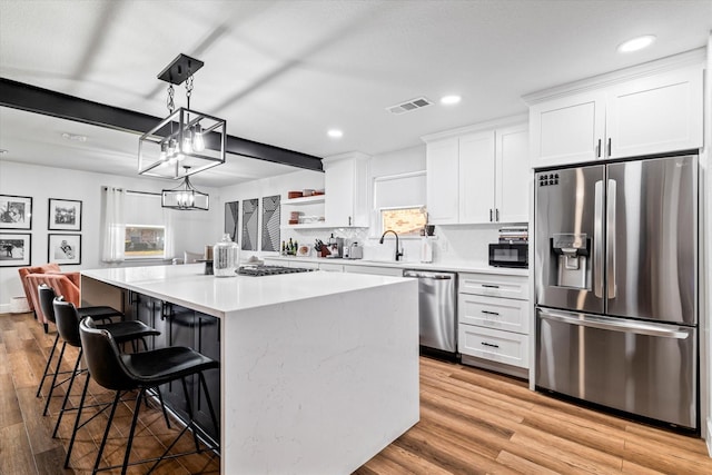 kitchen with a center island, hanging light fixtures, stainless steel appliances, a breakfast bar area, and white cabinets