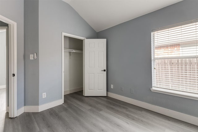 unfurnished bedroom with wood-type flooring, a closet, and lofted ceiling