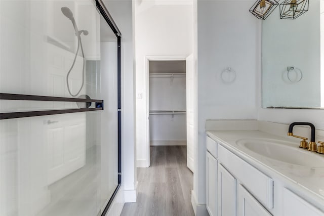 bathroom with hardwood / wood-style floors, vanity, and an enclosed shower