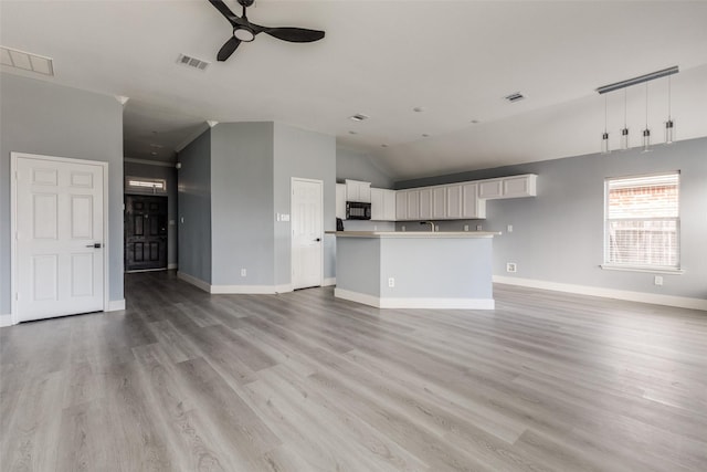 unfurnished living room with ceiling fan, light hardwood / wood-style floors, and vaulted ceiling