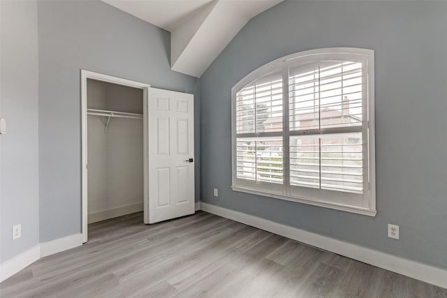 unfurnished bedroom with lofted ceiling, light hardwood / wood-style flooring, and a closet