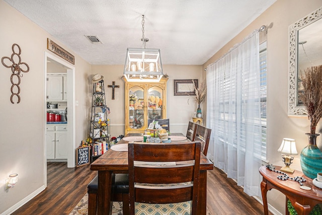 dining area with a textured ceiling and dark wood-type flooring