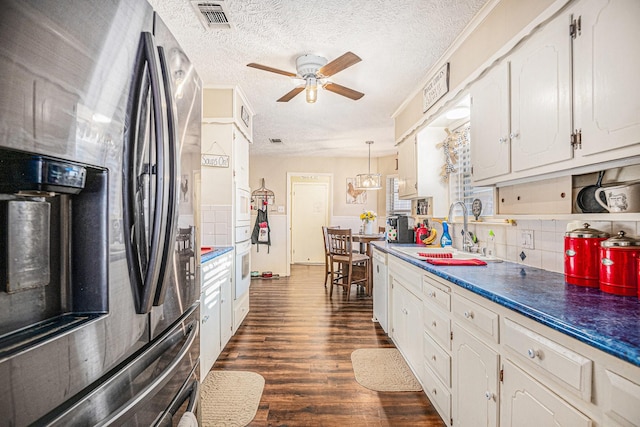 kitchen featuring white cabinets, stainless steel fridge, sink, and pendant lighting