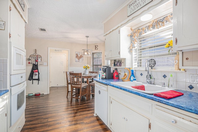 kitchen featuring decorative backsplash, white appliances, sink, pendant lighting, and white cabinetry