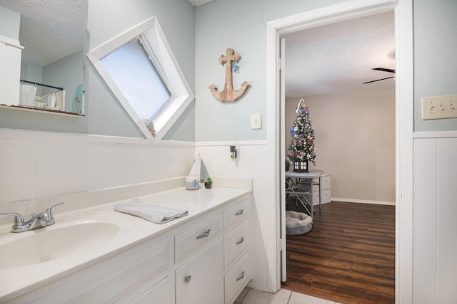 bathroom with ceiling fan, wood-type flooring, a textured ceiling, and vanity