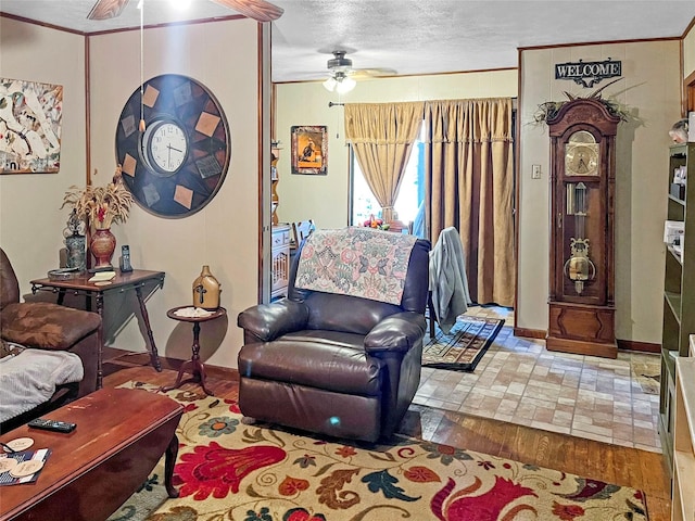 living room featuring ceiling fan, wood-type flooring, ornamental molding, and a textured ceiling