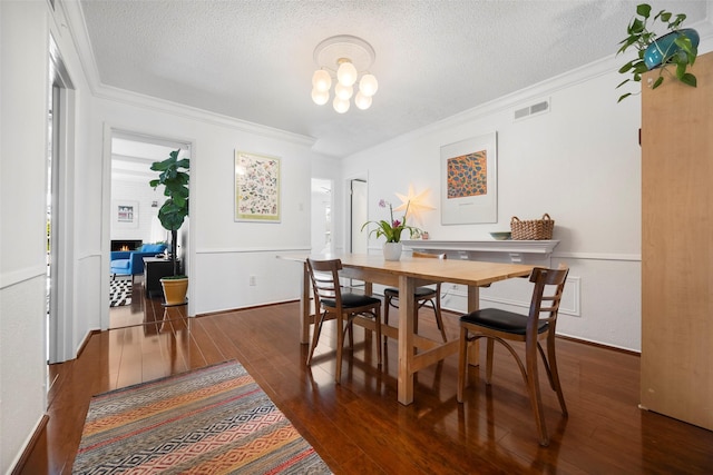 dining room with a textured ceiling, ornamental molding, a fireplace, and dark wood-type flooring