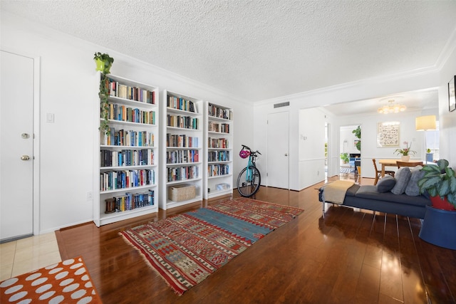 sitting room with hardwood / wood-style floors, a textured ceiling, and ornamental molding