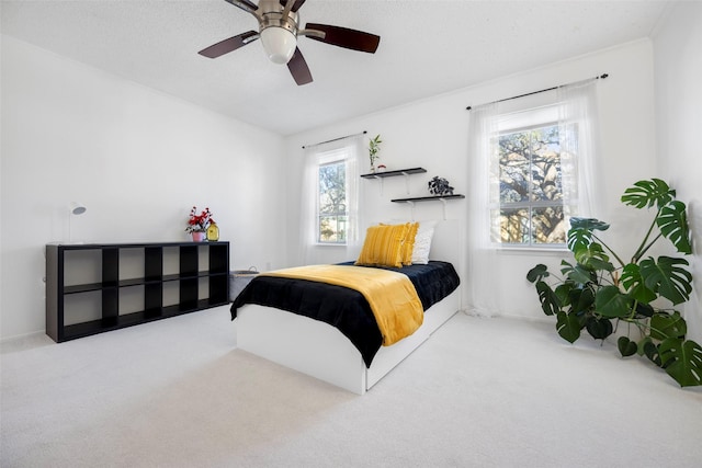 carpeted bedroom with ceiling fan and a textured ceiling