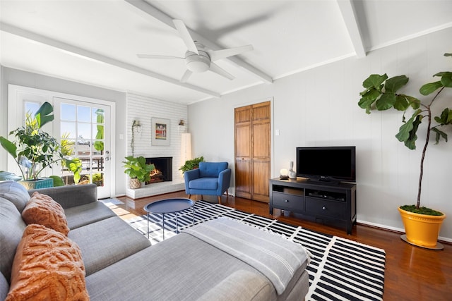 living room featuring beam ceiling, ceiling fan, a fireplace, and dark wood-type flooring