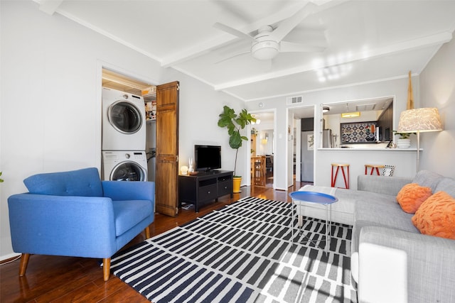 living room with stacked washer / drying machine, ceiling fan, beam ceiling, and dark hardwood / wood-style floors