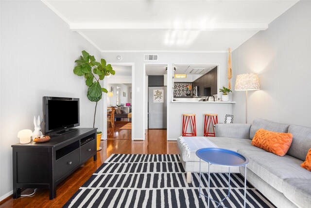 living room with beamed ceiling, dark hardwood / wood-style floors, and ornamental molding