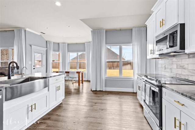 kitchen with sink, stainless steel appliances, backsplash, dark stone counters, and white cabinets