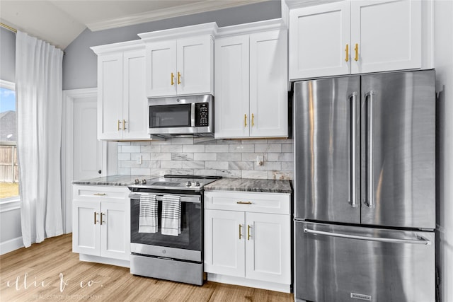 kitchen with stainless steel appliances, vaulted ceiling, stone countertops, decorative backsplash, and white cabinets