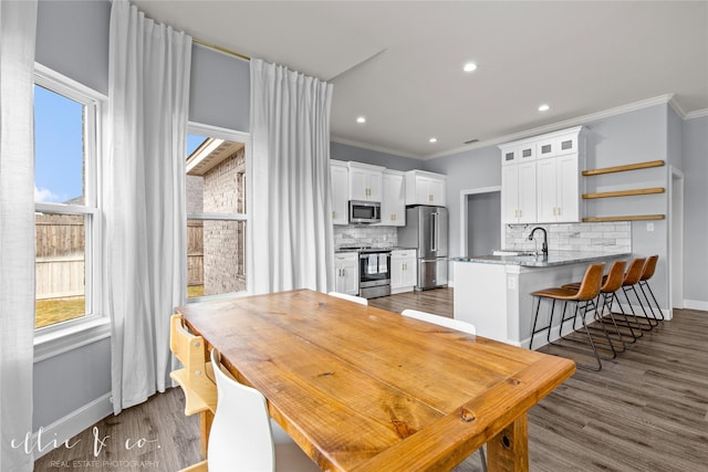 dining space with dark hardwood / wood-style floors, crown molding, and sink