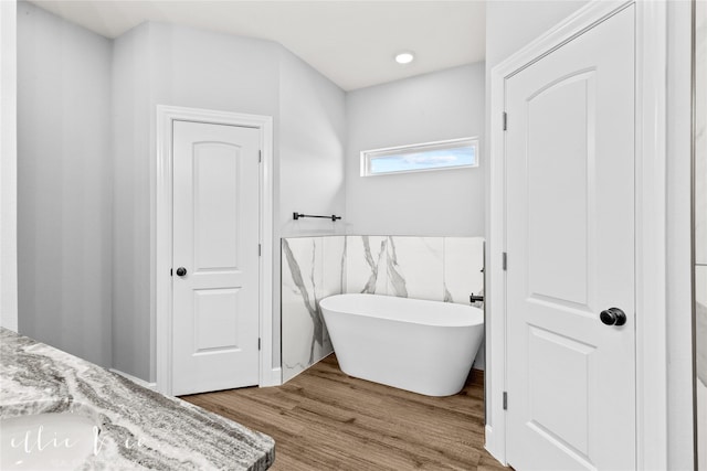 bathroom with hardwood / wood-style flooring, vanity, and a bathing tub