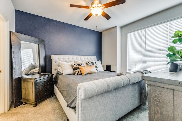 bedroom with multiple windows, ceiling fan, and light carpet