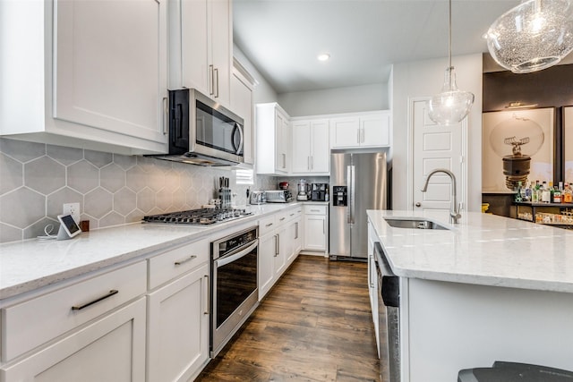 kitchen with light stone countertops, backsplash, stainless steel appliances, sink, and white cabinets